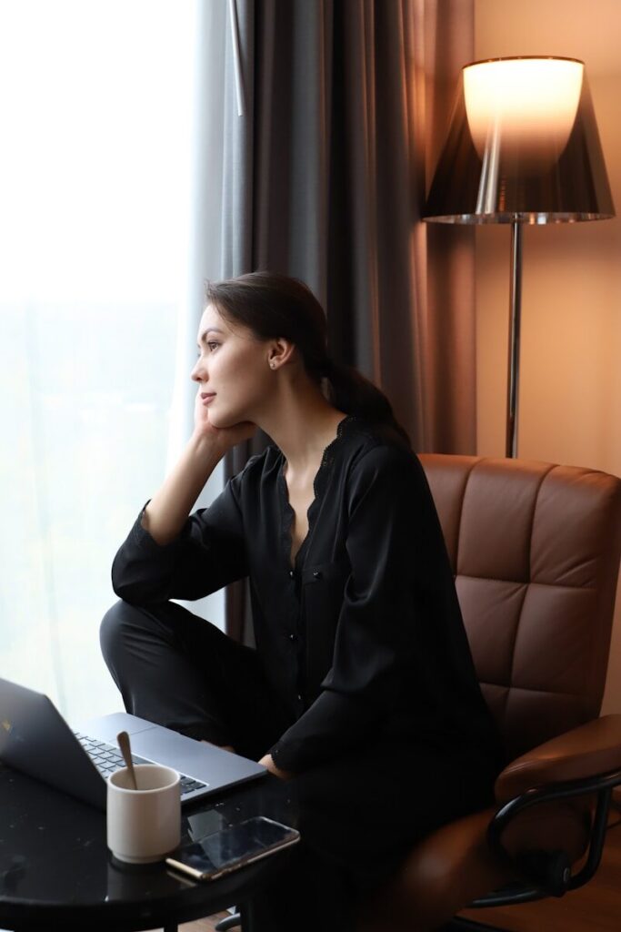 a woman sitting in a chair looking out a window