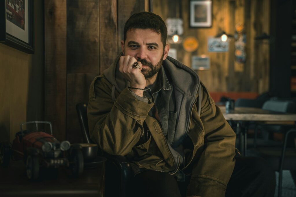 Man sitting with hand on chin in dimly lit room.